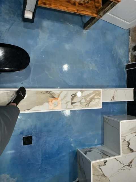 Blue metallic epoxy floor surrounding the fixtures in a finished bathroom