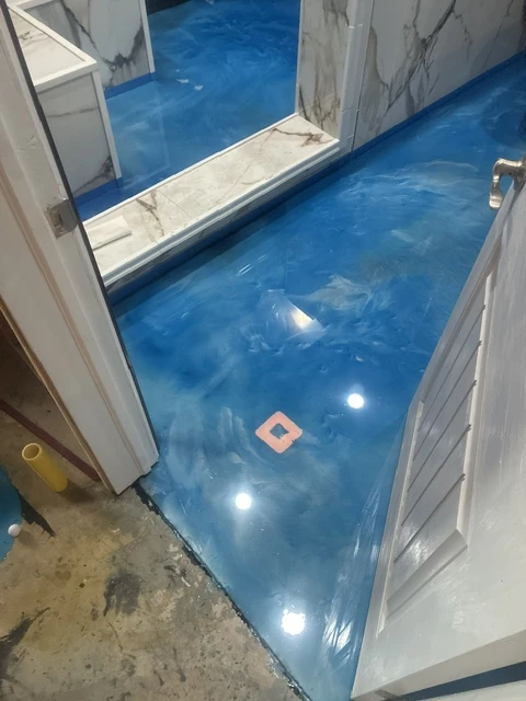 Glossy blue metallic epoxy floor installed beneath a bathroom vanity