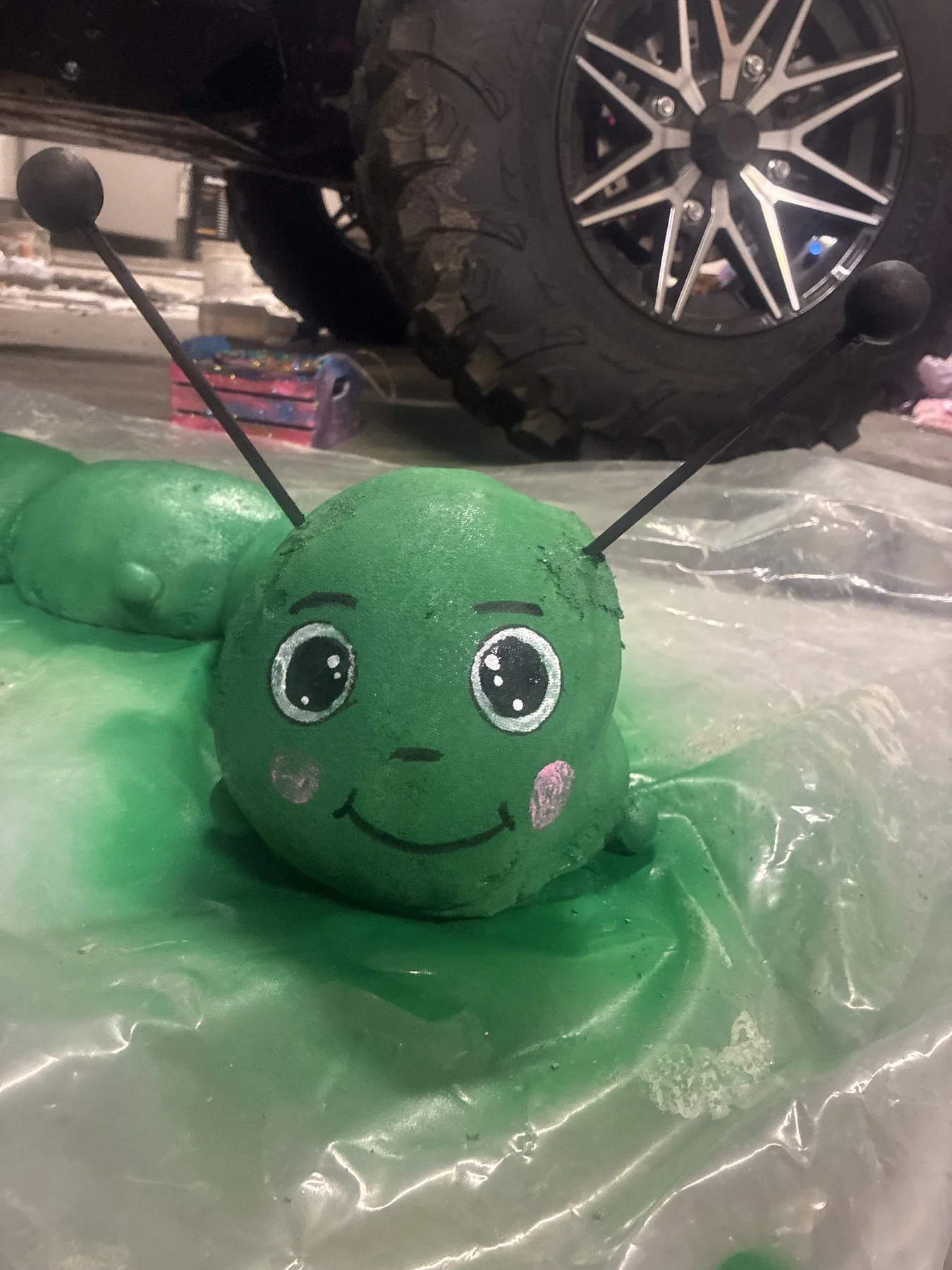 Hand-shaped green concrete caterpillar sculpture with a painted face
