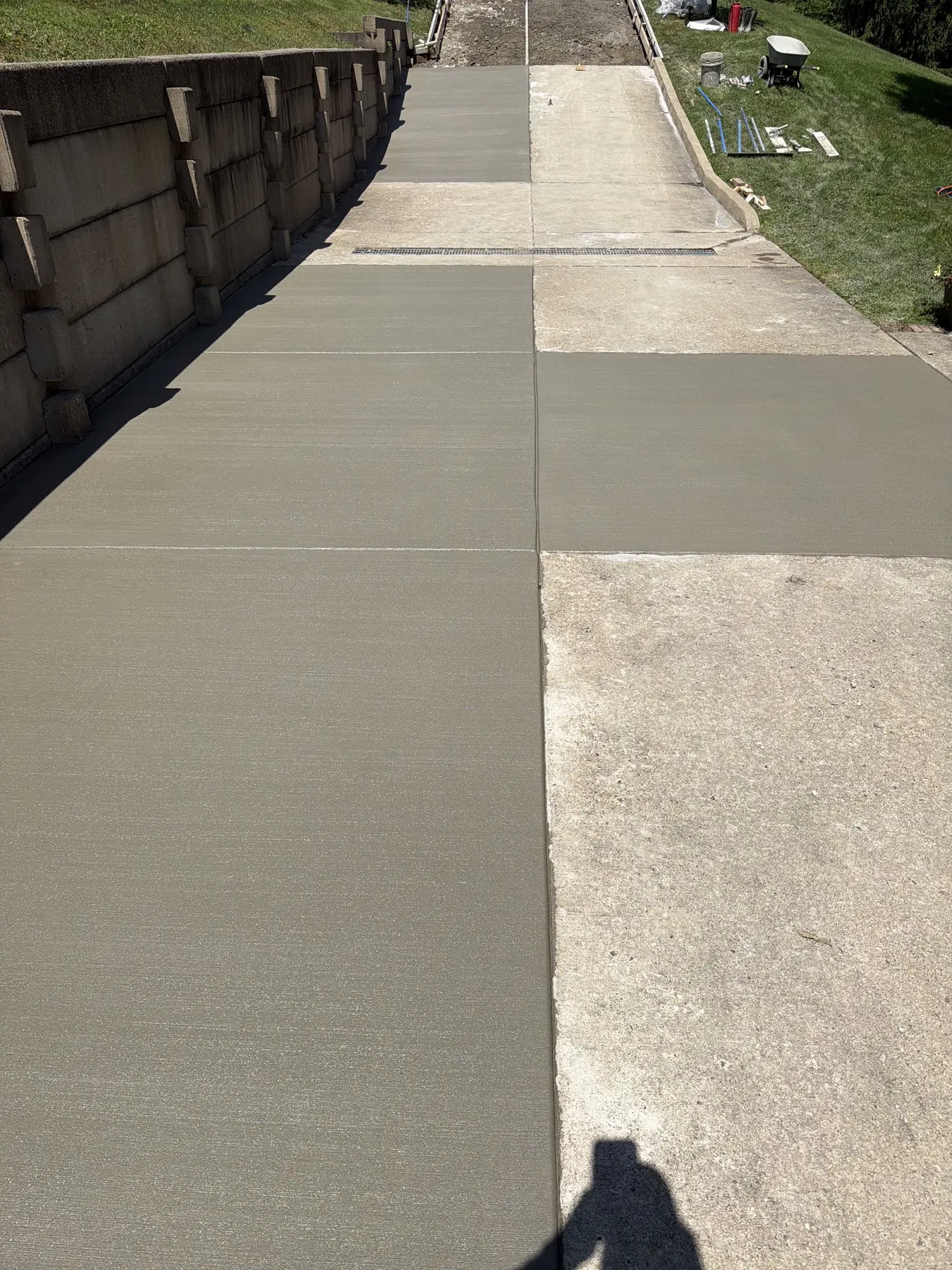 Finished concrete drive on a slope beside a block retaining wall
