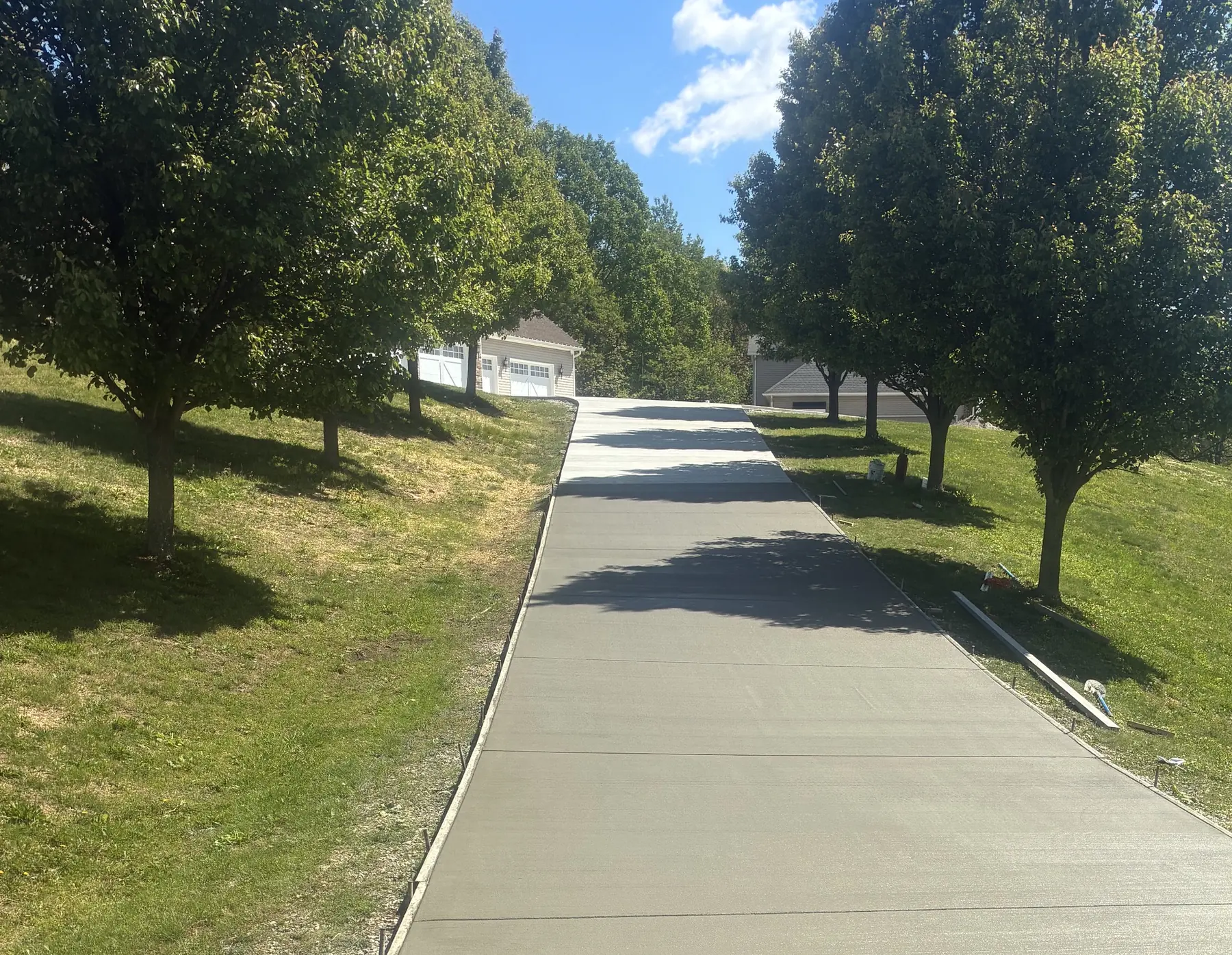 Long finished concrete driveway running through a sloped residential property