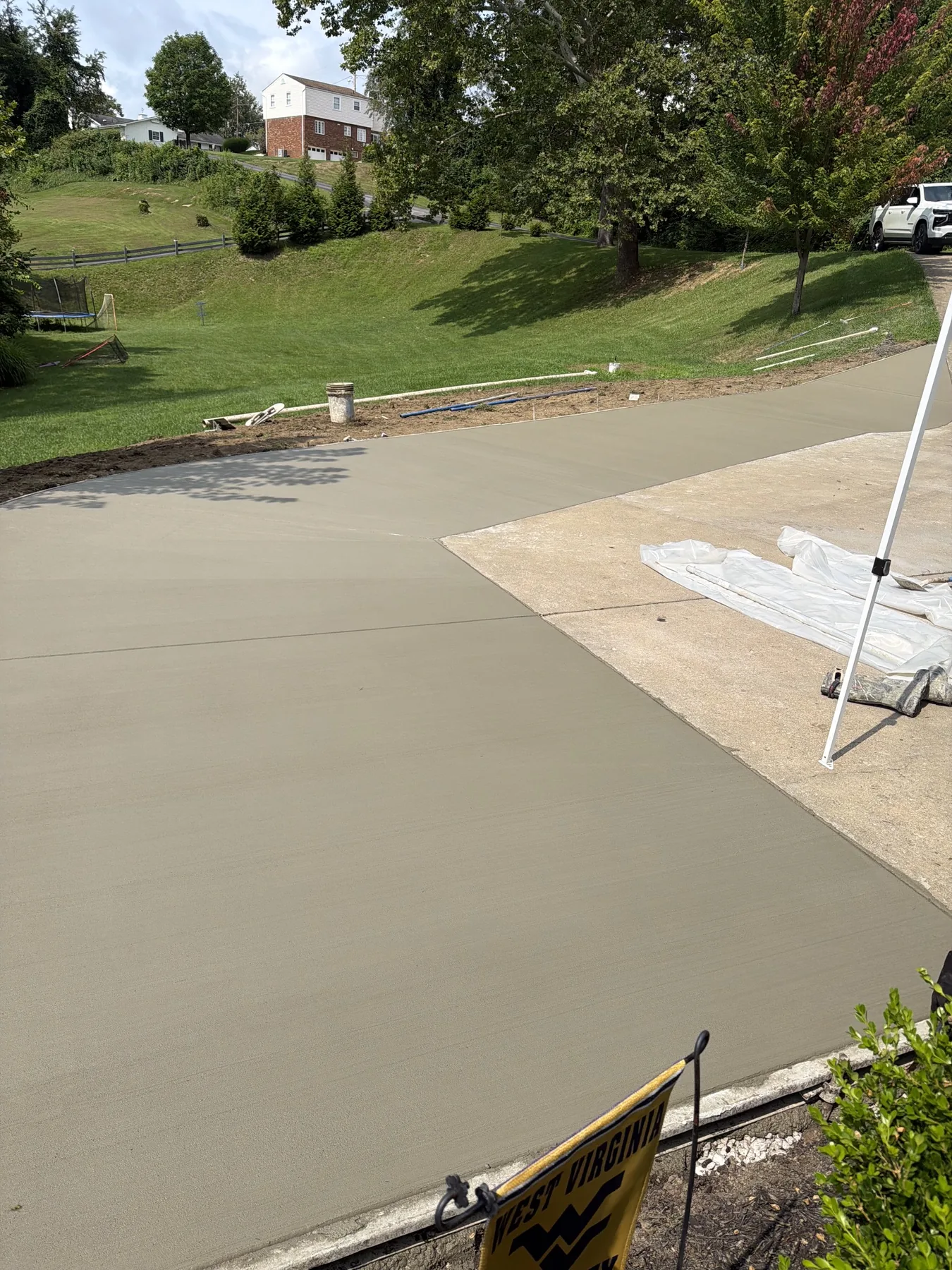 Fresh concrete driveway being finished on a hillside property