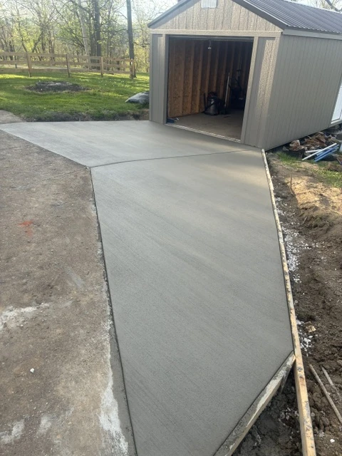 New concrete pad and approach installed beside a residential shed
