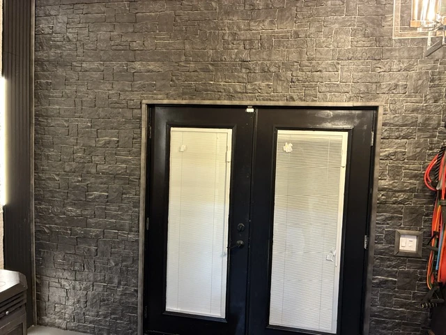 Dark stone veneer accent wall installed around interior double doors