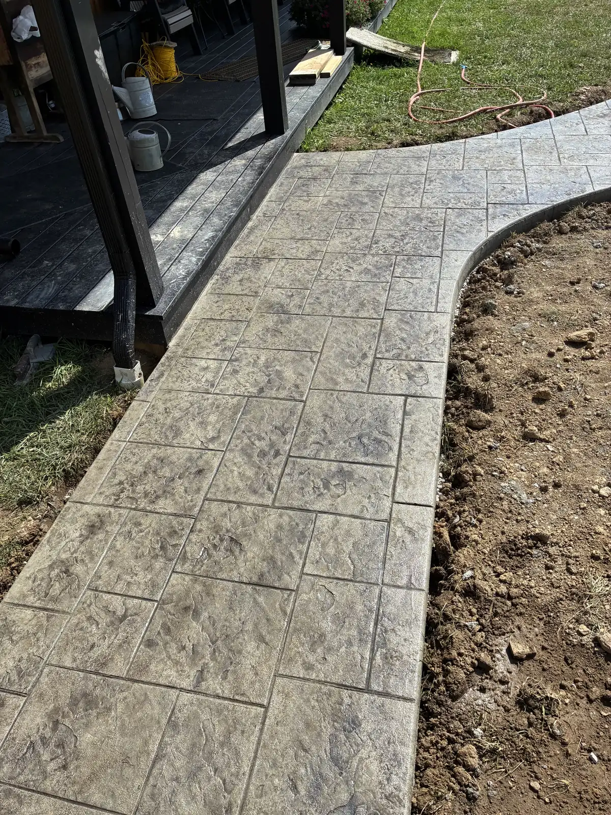 Stamped concrete walkway beside a covered outdoor living area