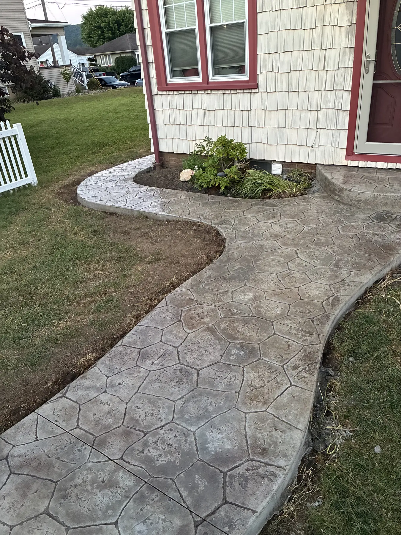 Stamped concrete walkway curving around a landscaped home entrance